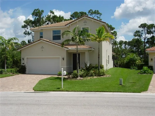 a front view of a house with a yard and potted plants