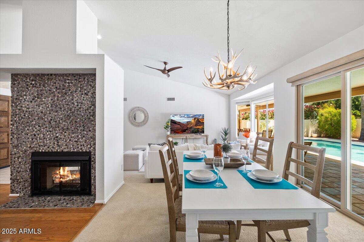 9081 East Sahuaro Drive Scottsdale, AZ 85260 - Photo 13 of 22 a dining room with furniture a fireplace and a chandelier