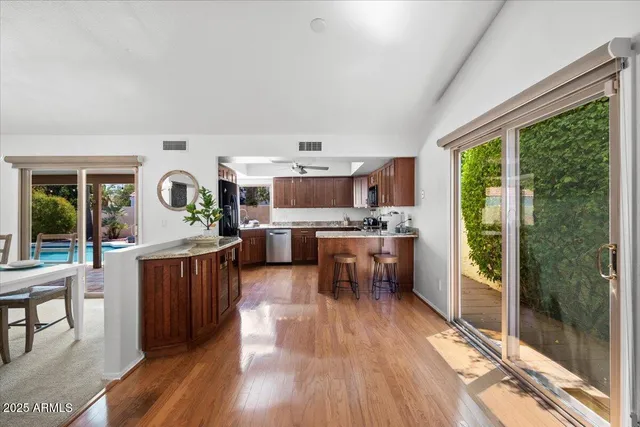 a open kitchen with granite countertop a stove top oven a sink and wooden floors