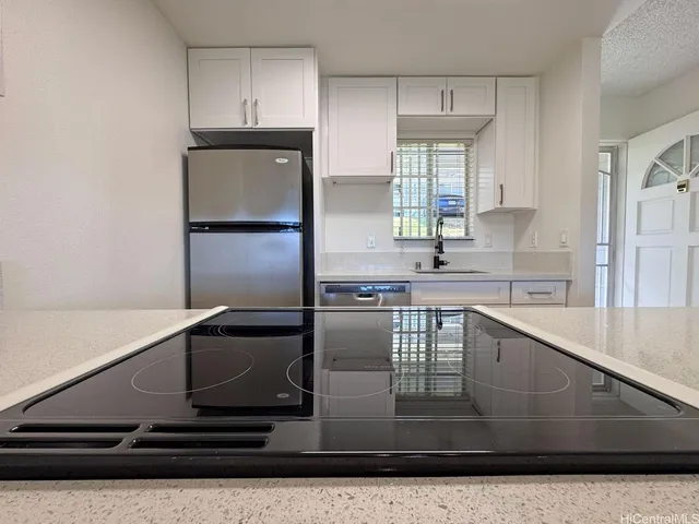 a kitchen with stainless steel appliances a sink cabinets and a window