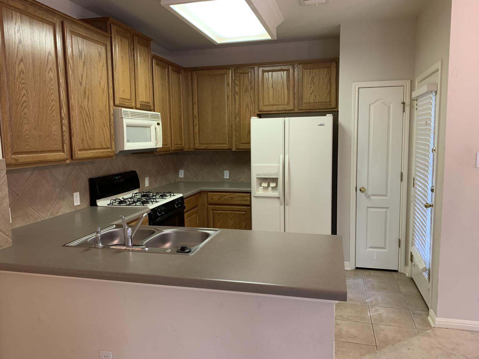 11000 Anderson Mill Road, Unit 29 Austin, TX 78750 - Photo 10 of 27 a kitchen with a refrigerator sink and cabinets
