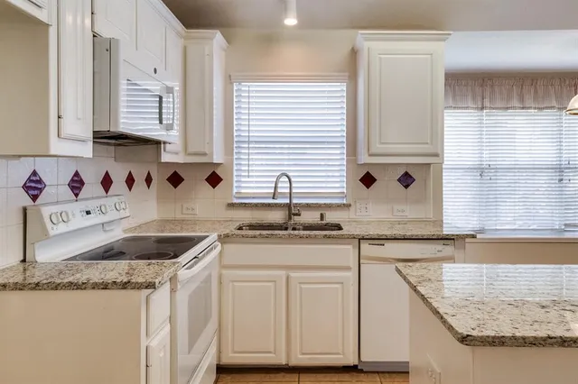 a kitchen with granite countertop a sink a window and cabinets