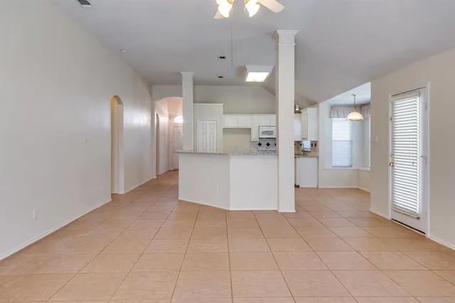 a view of a refrigerator in kitchen and an empty room