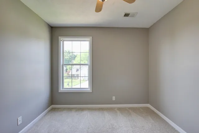 an empty room with a window and a fan