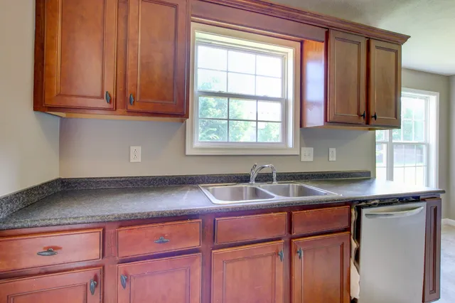 an empty room with wooden floor chandelier and windows