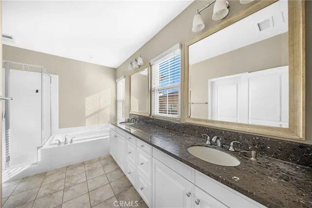 a bathroom with a granite countertop sink and a bathtub