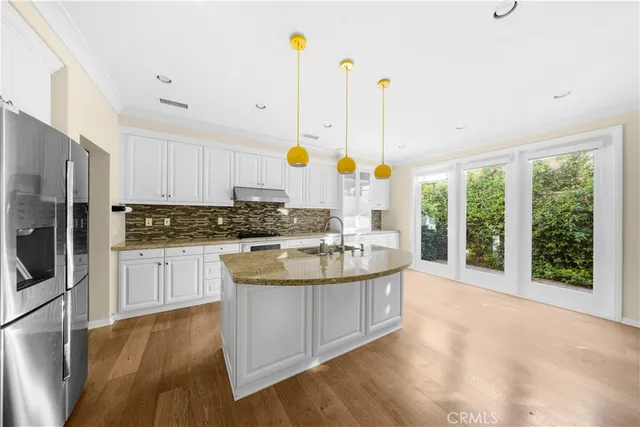 a kitchen with stainless steel appliances granite countertop a sink a stove and a wooden floors