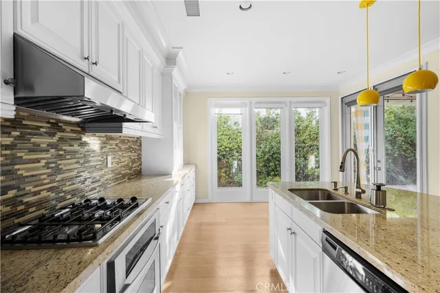 a kitchen with stainless steel appliances granite countertop a sink a stove and a wooden floors