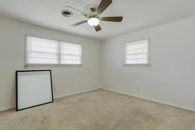 an empty room with a window and a ceiling fan