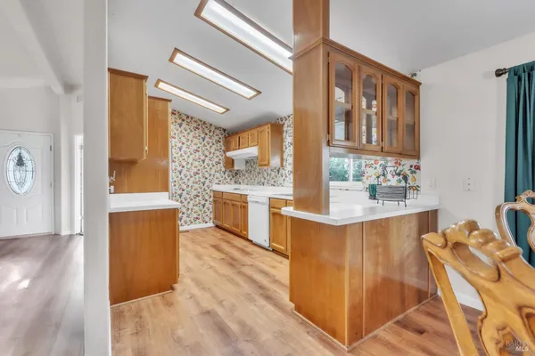 a kitchen with stainless steel appliances granite countertop a refrigerator a oven and white cabinets with wooden floors