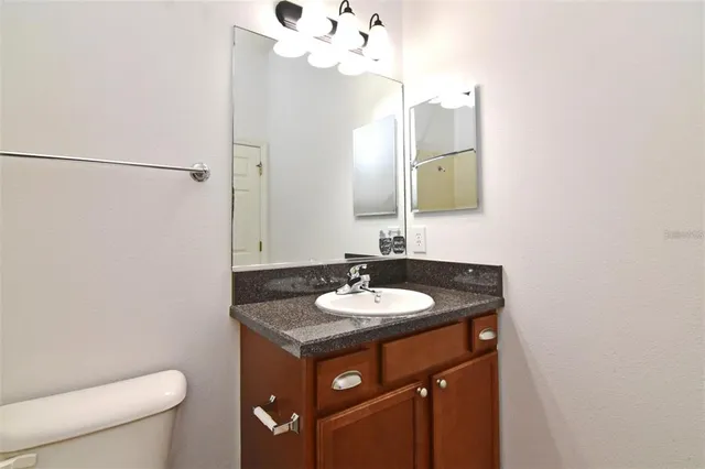 a bathroom with a granite countertop sink a toilet and a mirror
