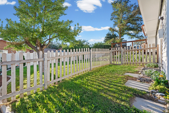 12152 Cinnamon Ridge Road Sandy, UT 84094 - Photo 20 of 34 Fenced backyard with mature shade trees, manicured lawn, and brick home exterior visible in background