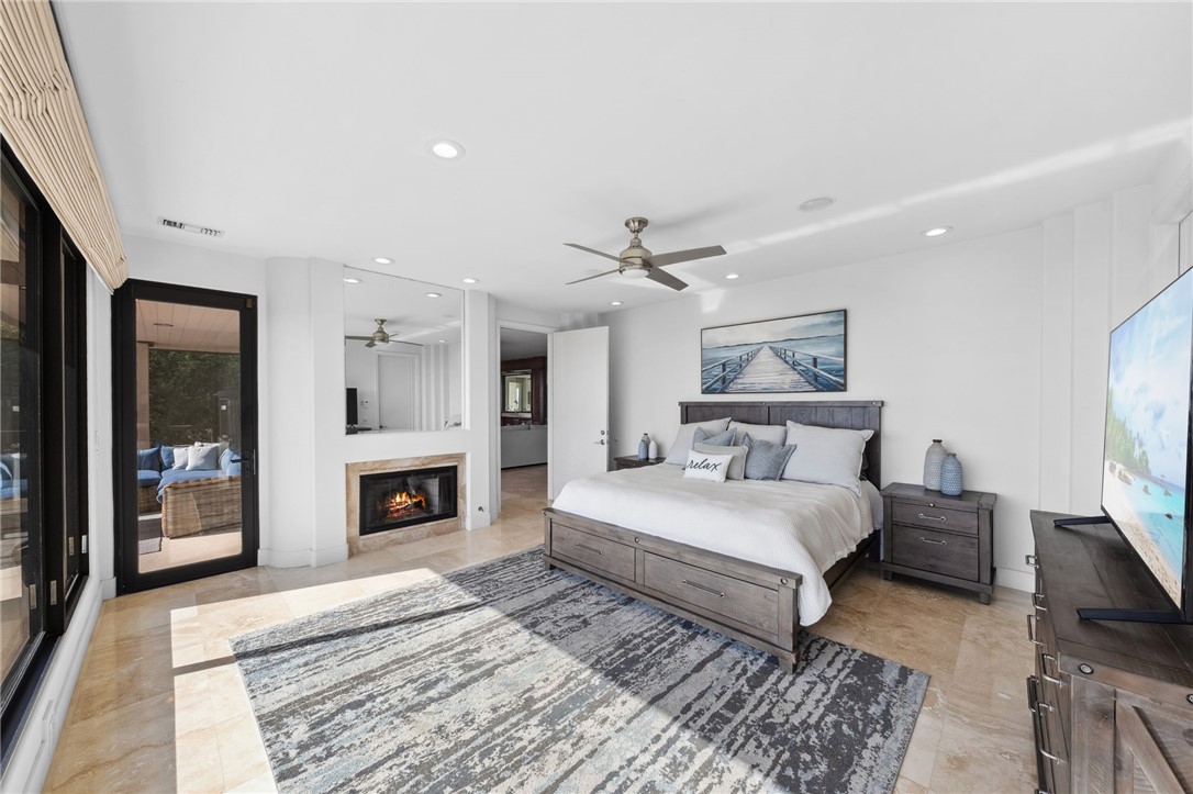 5381 Moonlight Lane La Jolla, CA 92037 - Photo 33 of 44 a spacious bedroom with a large bed a flat tv screen and a fireplace with wooden floor