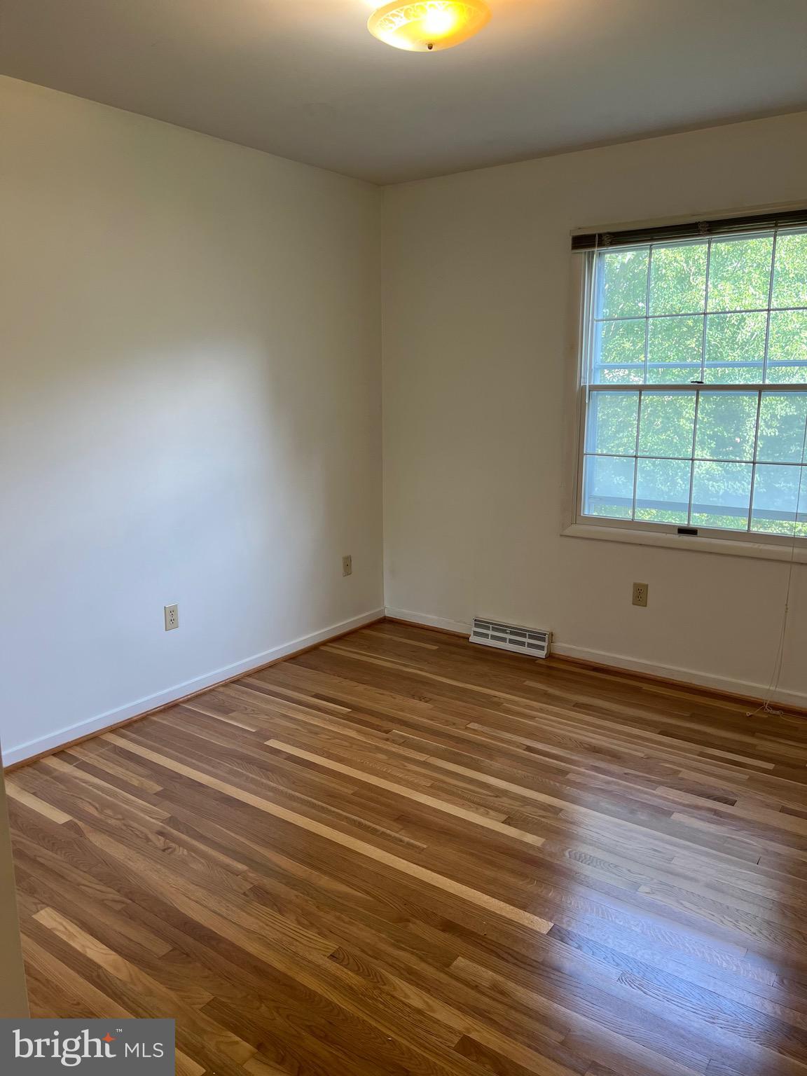 204 Pewter Lane Silver Spring, MD 20905 - Photo 7 of 12 an empty room with wooden floor and windows