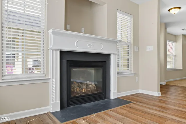 a view of an empty room with wooden floor fireplace and a window