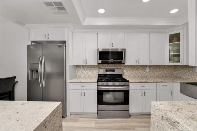 a large kitchen with stainless steel appliances kitchen island granite countertop a large counter top a sink a stove and a refrigerator