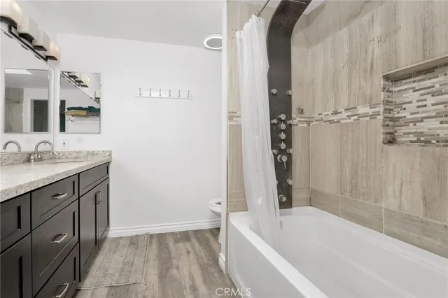 a bathroom with a granite countertop sink and mirror with bathtub