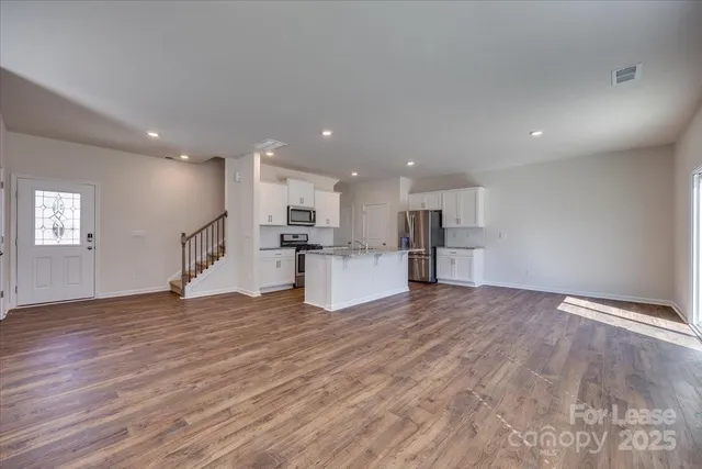 a view of kitchen with kitchen island wooden floor and refrigerator