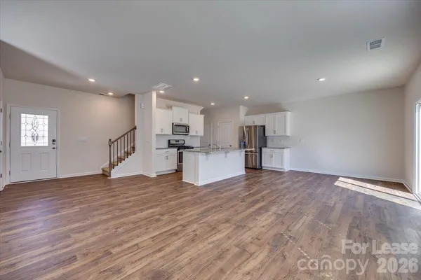 a view of kitchen with kitchen island wooden floor and refrigerator