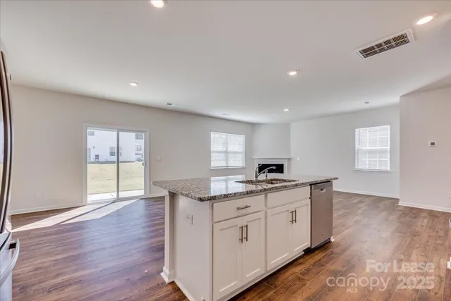 a kitchen with granite countertop a sink and cabinets with wooden floor