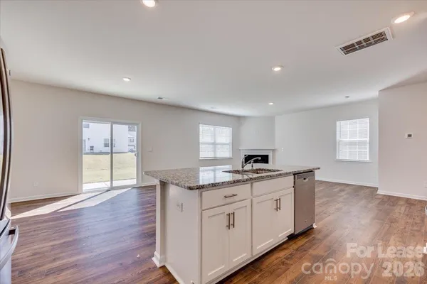 a kitchen with granite countertop a sink and cabinets with wooden floor