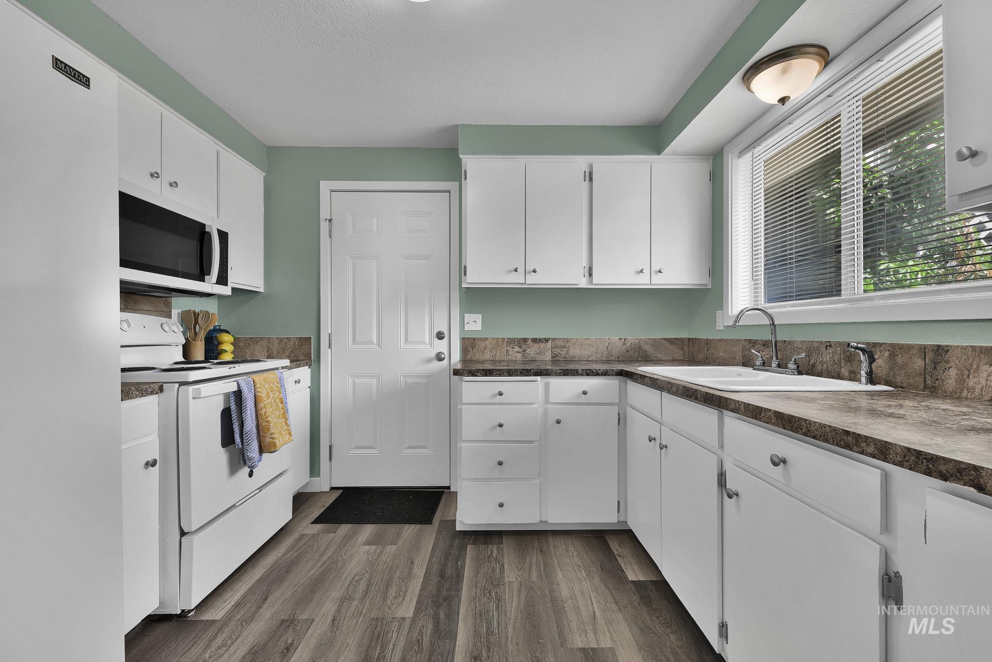 5755 Chuckwagon Road Nampa, ID 83686 - Photo 16 of 50 Kitchen featuring white cabinetry, wood-finish flooring, a stainless steel sink, and light green wall paint