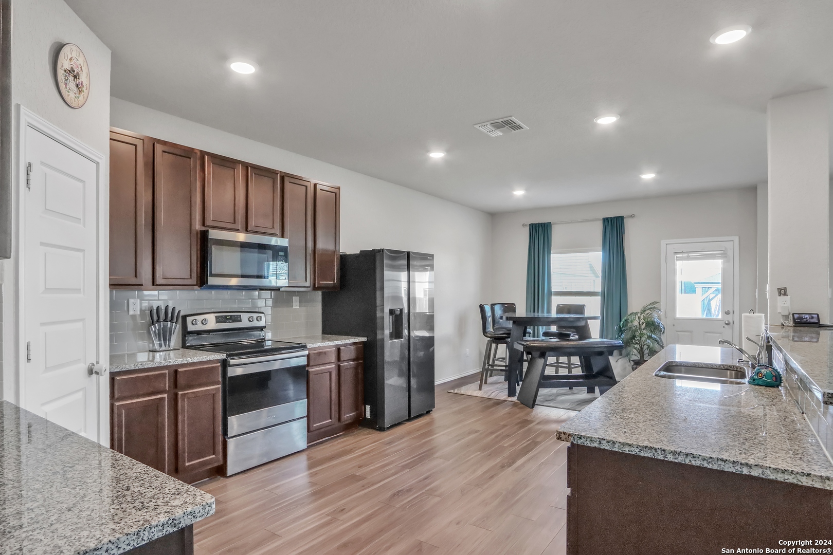 2425 Marty Way Seguin, TX 78155 - Photo 12 of 22 a kitchen with stainless steel appliances granite countertop a refrigerator a stove top oven a sink dishwasher a dining table and chairs with wooden floor