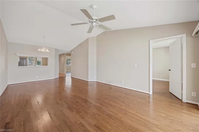a view of an empty room with wooden floor and a ceiling fan
