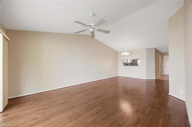 an empty room with wooden floor ceiling fan and windows