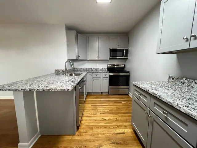 a kitchen with kitchen island granite countertop a sink stove and refrigerator