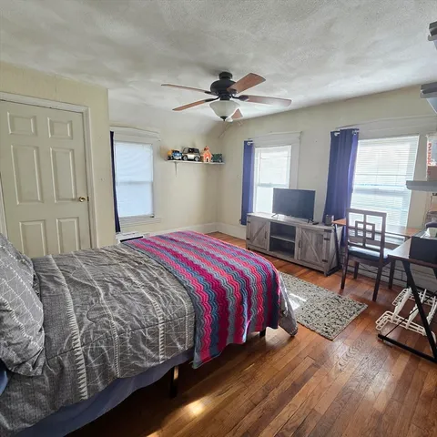 a bedroom with a bed a couch and dresser next to a window