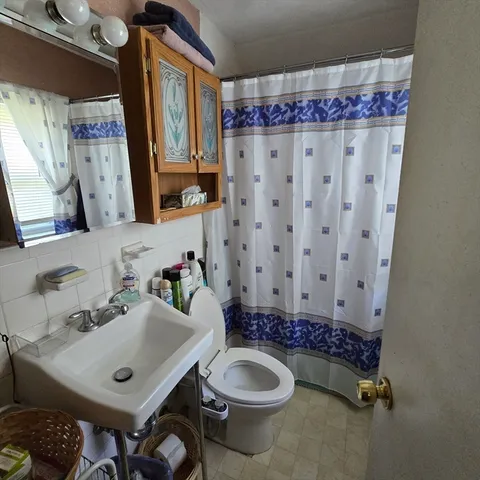 a bathroom with a sink a toilet and shower curtain