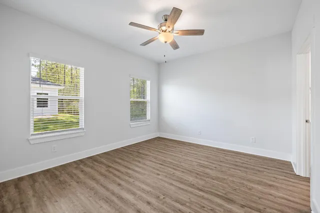 an empty room with wooden floor and windows
