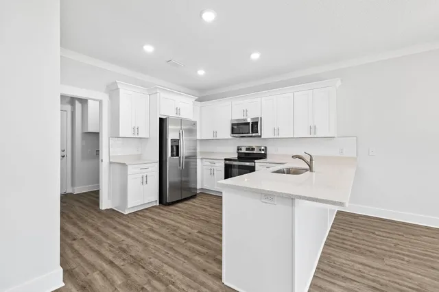 a kitchen with granite countertop white cabinets and stainless steel appliances