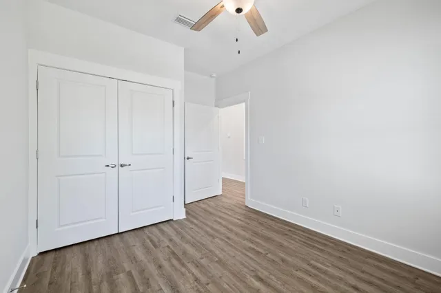 an empty room with windows and fan