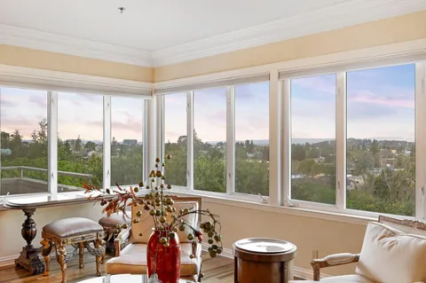 a view of a city from a dining room with furniture and floor to ceiling windows