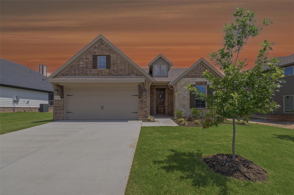 Brick and stone facade residence featuring a two-car garage, mature landscaping, and an inviting entryway
