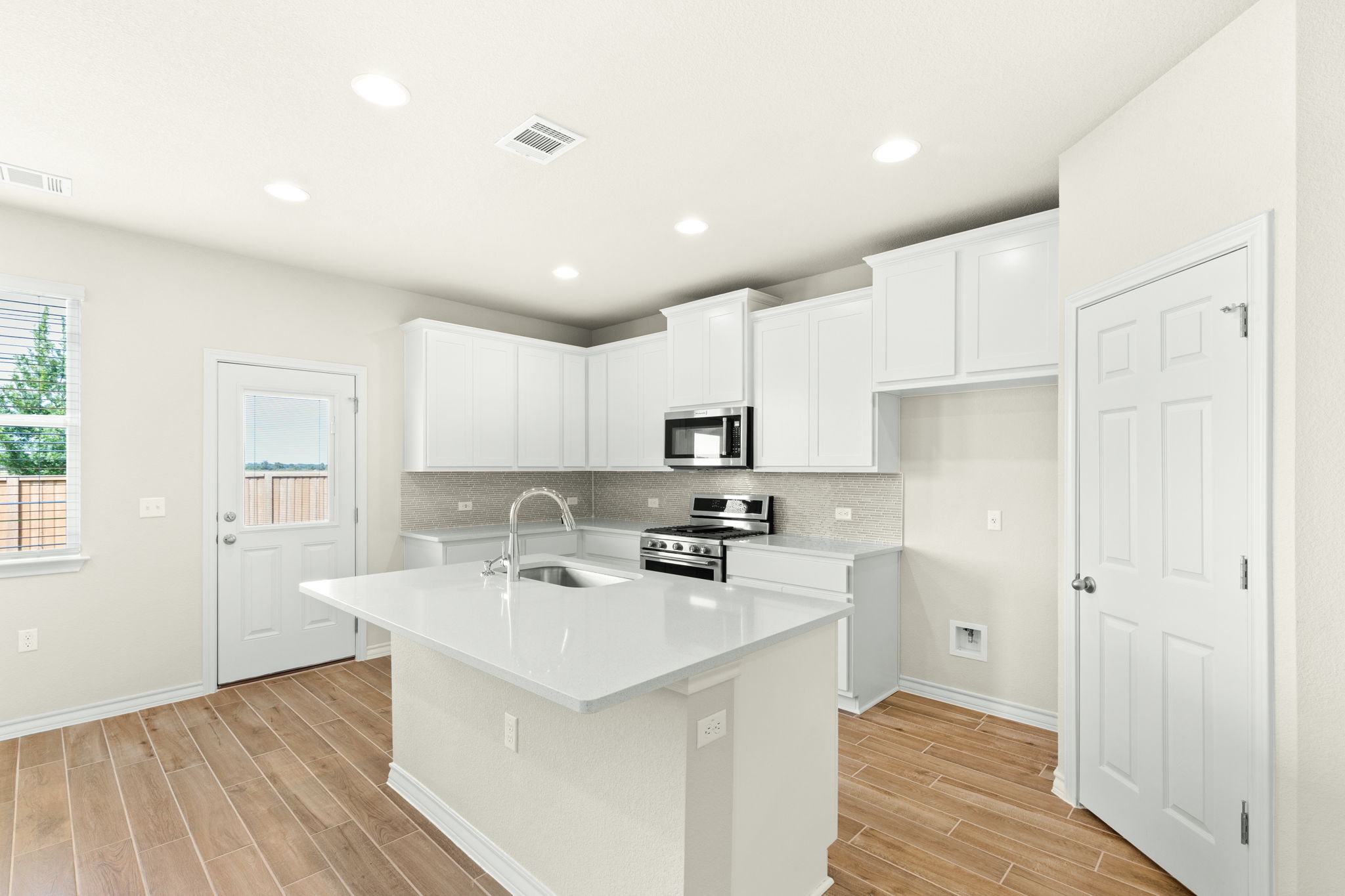 1624 Caballo Blanco Road Austin, TX 78725 - Photo 11 of 27 Recessed lighting illuminates wood-look tile floors and sleek cabinetry in this modern culinary space.