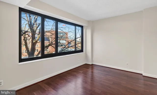 a view of an empty room with wooden floor and a window