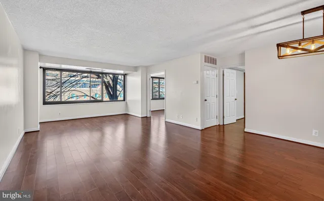 a view of an empty room with wooden floor and a window