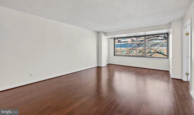 an empty room with wooden floor and window
