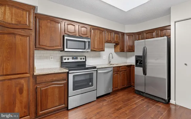 a kitchen with granite countertop stainless steel appliances and wooden cabinets