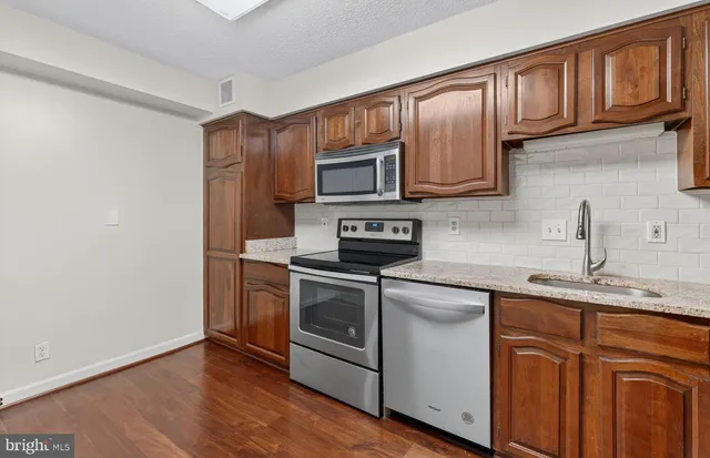 a kitchen with stainless steel appliances granite countertop a stove microwave and sink