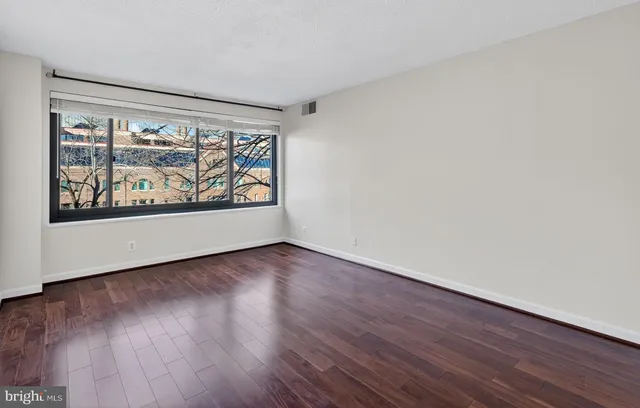 a view of an empty room with wooden floor and a window