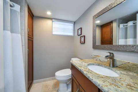a bathroom with a granite countertop sink a toilet and mirror