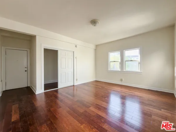 a view of an empty room with wooden floor and a window