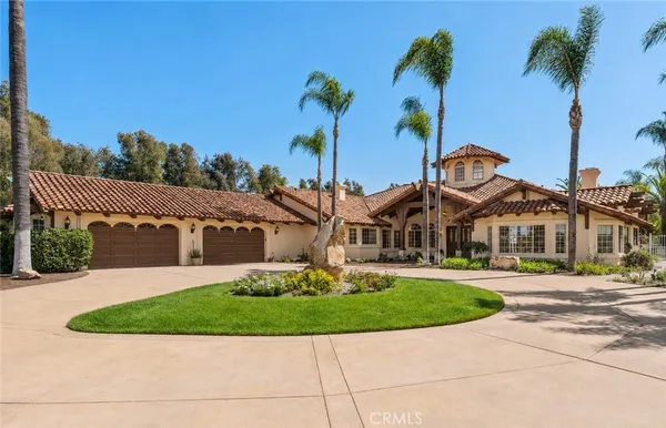 a front view of a house with a garden and palm trees