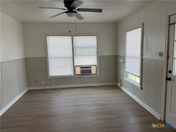 an empty room with wooden floor cabinet and windows