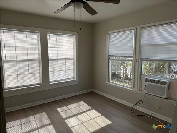 a view of an empty room with a window and wooden floor