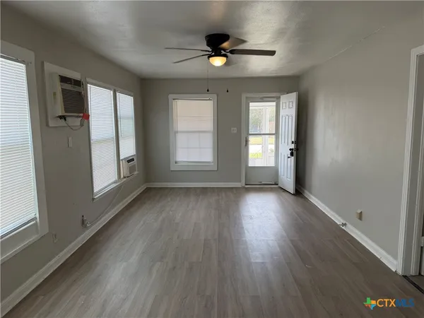 an empty room with wooden floor and windows